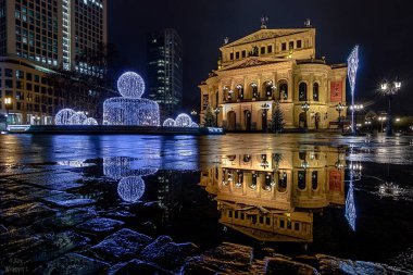 Akşam Frankfurt 'ta Alte Oper var. Almanya 'daki tarihi binanın mavi saatindeki güzel fotoğrafı. Sonbahar yağmuru ve ıslak toprak