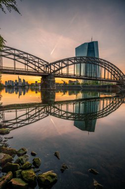 Frankfurt 'ta gün batımı. Skyline çelik köprünün altına sıkışmış. Nehrin kıyısında ve Frankfurt 'taki ECB' de.