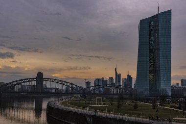 Frankfurt 'ta gün batımı. Skyline çelik köprünün altına sıkışmış. Nehrin kıyısında ve Frankfurt 'taki ECB' de.