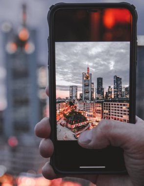 Frankfurt manzarası ve telefondaki her şey çok güzel. Bir cep telefonu (akıllı telefon) harika manzaranın önünde tutulur ve böylece cep telefonundaki ufuk çizgisini görebilirsiniz