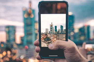 Frankfurt manzarası ve telefondaki her şey çok güzel. Bir cep telefonu (akıllı telefon) harika manzaranın önünde tutulur ve böylece cep telefonundaki ufuk çizgisini görebilirsiniz