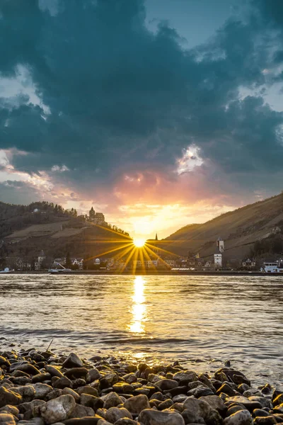 stock image view across the Rhine to Bacharach, historic small town in Germany, Mainz Bingen. Castle, church and vineyards. Sunset