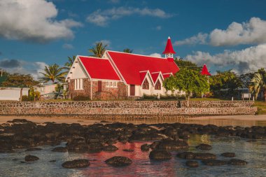 Sahilde gün batımı. Mauritius 'taki kırmızı çatılı ve denizin önündeki kilise. Cap malheureux