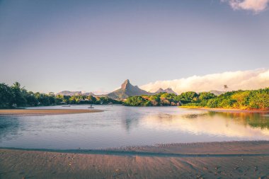 Mauritius 'ta bir Tamarin körfezinde gün batımı. Sörfçüler suda, dağlar da arka planda..