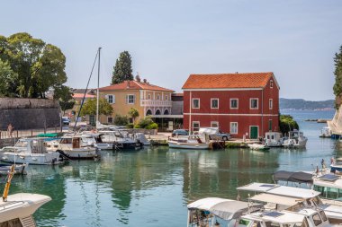 Zadarske gradske zidine, küçük tekneleri ve kendine özgü kırmızı bir evi olan tarihi liman. Adriyatik Denizi, Dalmaçya ve Hırvatistan 'ın eski Zadar kentinin etkileyici şehir duvarlarının önünde