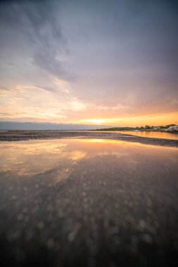 Beach in the morning. Sunrise, pebble beach on a rocky coast. The sky is reflected in the water of a bay. Natural spectacle of a Mediterranean landscape, island of Vir, Zadar, Dalmatia, Croatia, Adria clipart