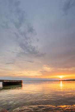 Beach in the morning. Sunrise, pebble beach on a rocky coast. The sky is reflected in the water of a bay. Natural spectacle of a Mediterranean landscape, island of Vir, Zadar, Dalmatia, Croatia, Adria clipart