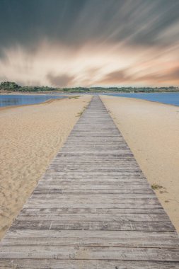 Her iki tarafında deniz olan bir sahil. Ortasında kumlu sahil boyunca uzanan tahta bir yaya köprüsü var. Akdeniz manzarası, Plaa drijac, Nin, Zadar, Dalmaçya, Hırvatistan