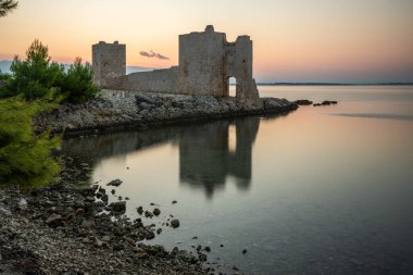 Şafak vakti kale harabeye döner. Akdeniz 'de güneş doğarken sakin sularla dolu bir körfez. Kastelina Kalesi, Vir Adası, Zadar, Dalmaçya, Hırvatistan, Adriyatik Denizi 'nin Gökyüzü ve Akdeniz manzarasının yansıması
