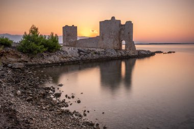 Şafak vakti kale harabeye döner. Akdeniz 'de güneş doğarken sakin sularla dolu bir körfez. Kastelina Kalesi, Vir Adası, Zadar, Dalmaçya, Hırvatistan, Adriyatik Denizi 'nin Gökyüzü ve Akdeniz manzarasının yansıması