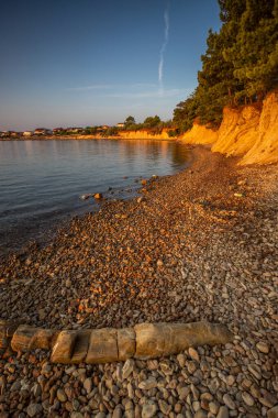 Beach in the morning. Sunrise, pebble beach on a rocky coast. The sky is reflected in the water of a bay. Natural spectacle of a Mediterranean landscape, island of Vir, Zadar, Dalmatia, Croatia, Adria clipart