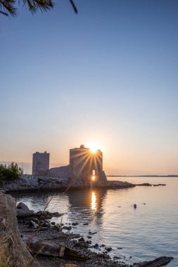 Şafak vakti kale harabeye döner. Akdeniz 'de güneş doğarken sakin sularla dolu bir körfez. Kastelina Kalesi, Vir Adası, Zadar, Dalmaçya, Hırvatistan, Adriyatik Denizi 'nin Gökyüzü ve Akdeniz manzarasının yansıması
