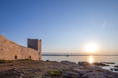 Rocky Sahili 'nde gün doğumu. Sakin sudaki yansıma. Akdeniz 'deki Kastelina Kalesi, Vir, Dalmaçya, Hırvatistan ve Adriyatik Denizi' nin yenilenmiş kalıntılarının manzara görüntüsü