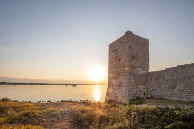 Rocky Sahili 'nde gün doğumu. Sakin sudaki yansıma. Akdeniz 'deki Kastelina Kalesi, Vir, Dalmaçya, Hırvatistan ve Adriyatik Denizi' nin yenilenmiş kalıntılarının manzara görüntüsü