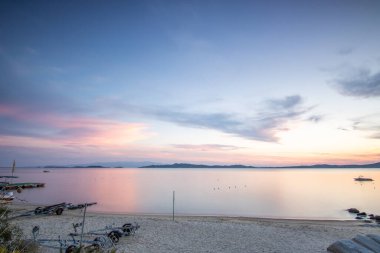 Kumlu bir sahildeki kayaların arasından gün batımına bak. Manzara, Ouranoupoli, Selanik, Orta Makedonya ve Yunanistan kıyılarındaki engin deniz manzarası ile çekildi