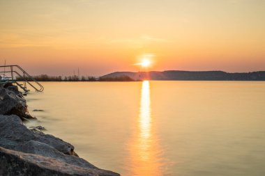 Yazın bir gölün kıyısında gün batımı. Horiont 'u geniş görüşlü, renkli bir gökyüzü. Balaton, Balaton Gölü, Sifok, Macaristan 'da doğa manzarası