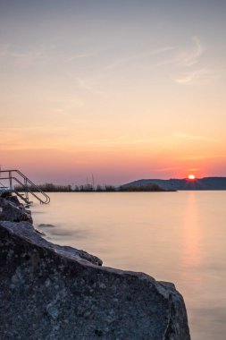 Yazın bir gölün kıyısında gün batımı. Horiont 'u geniş görüşlü, renkli bir gökyüzü. Balaton, Balaton Gölü, Sifok, Macaristan 'da doğa manzarası