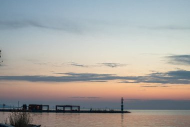 Yazın sahilde gün doğumu ve bir gölün limanı. Horiont 'u geniş görüşlü, renkli bir gökyüzü. Doğa manzarası Tihany marinası, Balaton, Balaton Gölü, Sifok, Macaristan