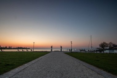 Yazın sahilde gün doğumu ve bir gölün limanı. Horiont 'u geniş görüşlü, renkli bir gökyüzü. Doğa manzarası Balatonfred Vitorlskikt, Balaton, Balaton Gölü, Sifok, Macaristan