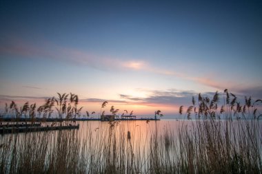 Yazın sahilde gün doğumu ve bir gölün limanı. Horiont 'u geniş görüşlü, renkli bir gökyüzü. Doğa manzarası Tihany marinası, Balaton, Balaton Gölü, Sifok, Macaristan