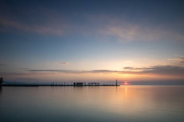 Yazın sahilde gün doğumu ve bir gölün limanı. Horiont 'u geniş görüşlü, renkli bir gökyüzü. Doğa manzarası Tihany marinası, Balaton, Balaton Gölü, Sifok, Macaristan