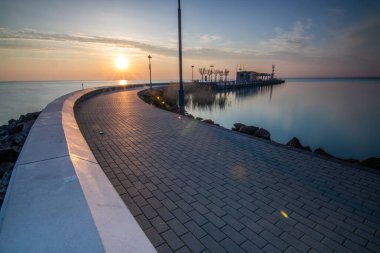 Yazın sahilde gün doğumu ve bir gölün limanı. Horiont 'u geniş görüşlü, renkli bir gökyüzü. Doğa manzarası Tihany marinası, Balaton, Balaton Gölü, Sifok, Macaristan