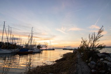 Büyük bir gölde fantastik bir gün batımı. Kıyıda durmuş gölün karşısındaki ufka bakarak güneşe doğru. Macaristan, Balaton Gölü 'nde romantik manzara