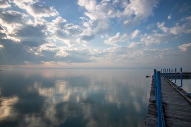 Sakin bir gölün kıyısından alınan su manzarası. Gün batımında ufka yansıyan suyun üzerinden bak. Siofok limanında bir iskele ya da iskele, Balaton, Macaristan