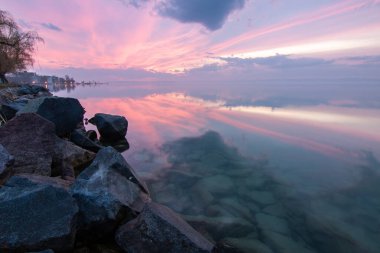 Sakin bir gölün kıyısından alınan su manzarası. Gün batımında ufka yansıyan suyun üzerinden bak. Siofok Limanı, Balaton, Macaristan
