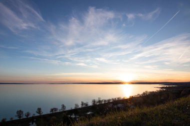 Akşamları bir gölün üzerindeki tepeden manzara. Doğada güzel bir manzara. Balatonakarattya, Balaton, Macaristan 'da romantik gün batımı