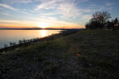 Akşamları bir gölün üzerindeki tepeden manzara. Doğada güzel bir manzara. Balatonakarattya, Balaton, Macaristan 'da romantik gün batımı