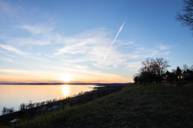 Akşamları bir gölün üzerindeki tepeden manzara. Doğada güzel bir manzara. Balatonakarattya, Balaton, Macaristan 'da romantik gün batımı