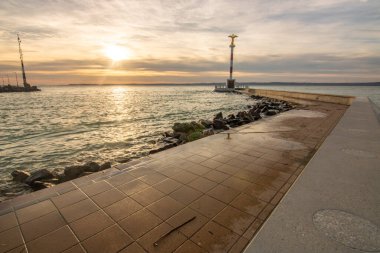 Gölde küçük bir marina. Dalgakıran ve altın şekilli sütun rüya gibi gün batımında. Sifok, Balaton, Macaristan 'da manzara çekimi