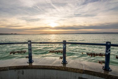 a small marina on a lake. Breakwater and pillar with golden figure in the dreamy sunset. Landscape shot in Sifok, Balaton, Hungary clipart