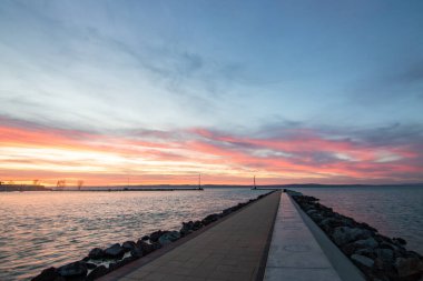 Gölde küçük bir marina. Dalgakıran ve altın şekilli sütun rüya gibi gün batımında. Sifok, Balaton, Macaristan 'da manzara çekimi