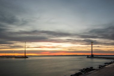 Gölde küçük bir marina. Dalgakıran ve altın şekilli sütun rüya gibi gün batımında. Sifok, Balaton, Macaristan 'da manzara çekimi