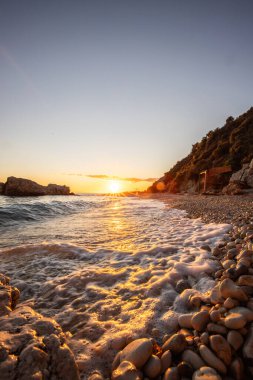 Gün doğumunda gizli körfez. Küçük kuma, çakıl taşına, sıcak renklerde plaja ve sabah ışığına baktım. Xigia Sülfür Plajları 'ndaki deniz manzarası, İyon Adaları, Yunanistan