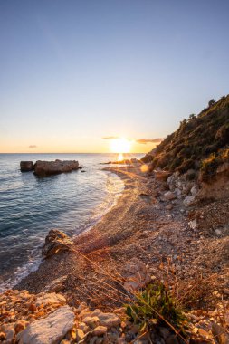 Gün doğumunda gizli körfez. Küçük kuma, çakıl taşına, sıcak renklerde plaja ve sabah ışığına baktım. Xigia Sülfür Plajları 'ndaki deniz manzarası, İyon Adaları, Yunanistan