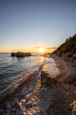 Gün doğumunda gizli körfez. Küçük kuma, çakıl taşına, sıcak renklerde plaja ve sabah ışığına baktım. Xigia Sülfür Plajları 'ndaki deniz manzarası, İyon Adaları, Yunanistan