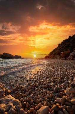 Gün doğumunda gizli körfez. Küçük kuma, çakıl taşına, sıcak renklerde plaja ve sabah ışığına baktım. Xigia Sülfür Plajları 'ndaki deniz manzarası, İyon Adaları, Yunanistan