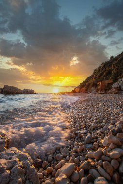 Gün doğumunda gizli körfez. Küçük kuma, çakıl taşına, sıcak renklerde plaja ve sabah ışığına baktım. Xigia Sülfür Plajları 'ndaki deniz manzarası, İyon Adaları, Yunanistan