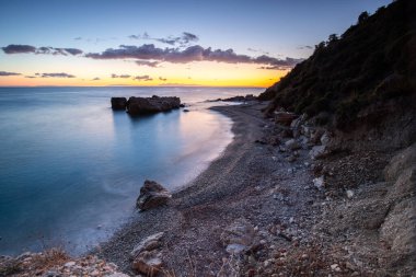 Gün doğumunda gizli körfez. Küçük kuma, çakıl taşına, sıcak renklerde plaja ve sabah ışığına baktım. Xigia Sülfür Plajları 'ndaki deniz manzarası, İyon Adaları, Yunanistan
