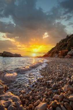 Gün doğumunda gizli körfez. Küçük kuma, çakıl taşına, sıcak renklerde plaja ve sabah ışığına baktım. Xigia Sülfür Plajları 'ndaki deniz manzarası, İyon Adaları, Yunanistan