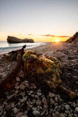 Gün doğumunda gizli körfez. Küçük kuma, çakıl taşına, sıcak renklerde plaja ve sabah ışığına baktım. Xigia Sülfür Plajları 'ndaki deniz manzarası, İyon Adaları, Yunanistan