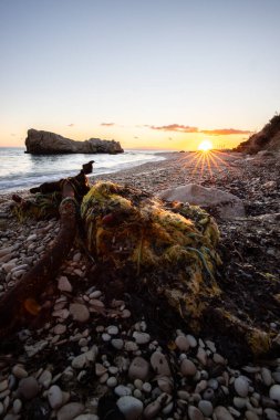 Gün doğumunda gizli körfez. Küçük kuma, çakıl taşına, sıcak renklerde plaja ve sabah ışığına baktım. Xigia Sülfür Plajları 'ndaki deniz manzarası, İyon Adaları, Yunanistan