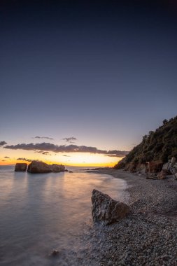 Gün doğumunda gizli körfez. Küçük kuma, çakıl taşına, sıcak renklerde plaja ve sabah ışığına baktım. Xigia Sülfür Plajları 'ndaki deniz manzarası, İyon Adaları, Yunanistan