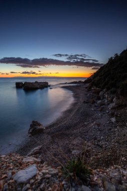 Gün doğumunda gizli körfez. Küçük kuma, çakıl taşına, sıcak renklerde plaja ve sabah ışığına baktım. Xigia Sülfür Plajları 'ndaki deniz manzarası, İyon Adaları, Yunanistan