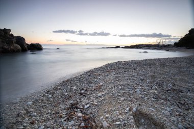 Gün doğumunda gizli körfez. Küçük kuma, çakıl taşına, sıcak renklerde plaja ve sabah ışığına baktım. Xigia Sülfür Plajları 'ndaki deniz manzarası, İyon Adaları, Yunanistan