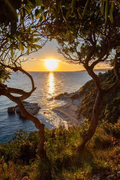 Скрытый залив на рассвете. Смотрел на мелкий песок, гальку, пляж в теплых тонах и утренний свет. Вид на море на серных пляжах Сиа, Ионические острова, Греция