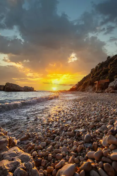 Gün doğumunda gizli körfez. Küçük kuma, çakıl taşına, sıcak renklerde plaja ve sabah ışığına baktım. Xigia Sülfür Plajları 'ndaki deniz manzarası, İyon Adaları, Yunanistan